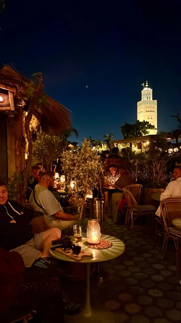Evening rooftop dining in Marrakech with the illuminated Koutoubia Mosque in the background